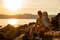 Young Couple Kissing And Drinking Beer While Sitting On Rocks - PhotoDune Item for Sale