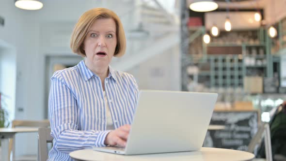 Creative Old Woman with Laptop Shocked in Cafe