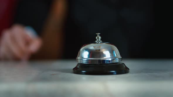 The Hand of a Man in a Suit Hits the Hotel Bell.