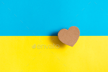 The concept is no war in Ukraine. Cardboard heart on the background of the Ukrainian flag. Top view.