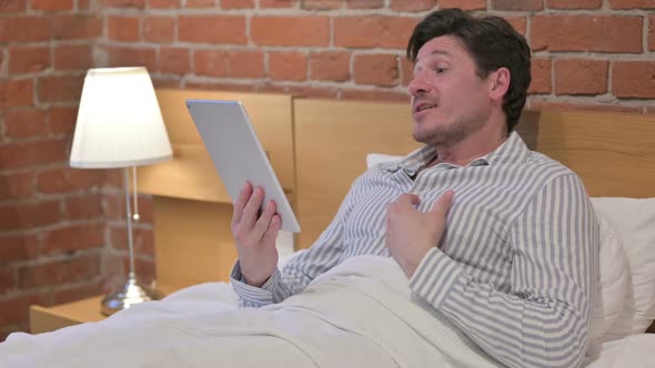 Middle Aged Man doing Video Call on Tablet in Bed