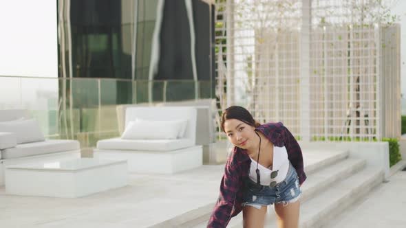 Attractive Asian woman smiling  play skateboard outdoor