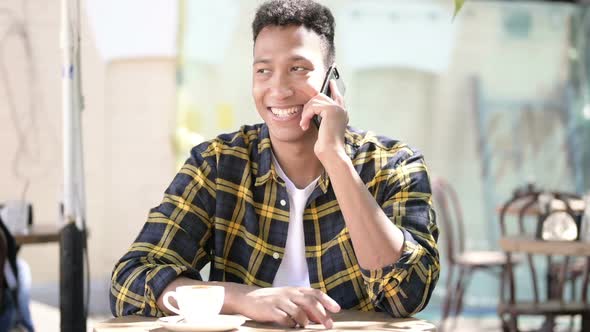 Happy Young African Man Talking on Phone Outdoor Cafe