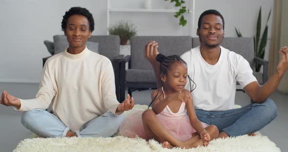 Young Afro American Family with Little Funny Daughter Sitting Together on Floor Doing Breath