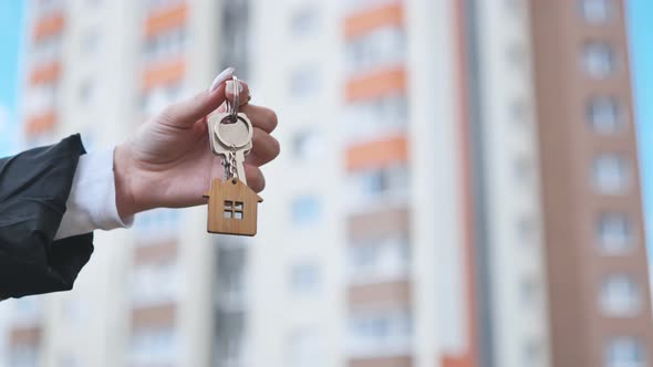 Girl Holding Keys to Apartment Against the Backdrop of an Apartment Building