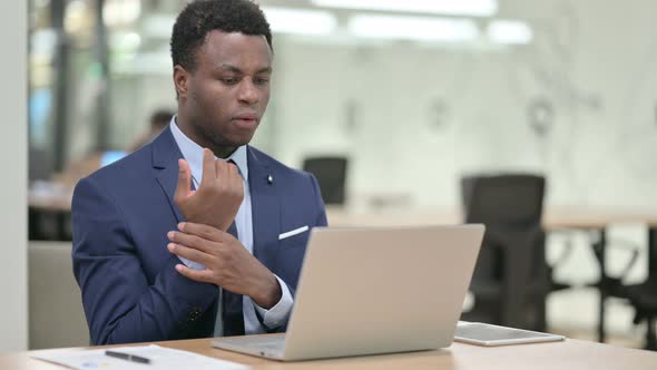 African Businessman Having Wrist Pain While Working on Laptop