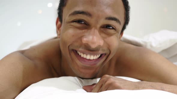 Yes by African Man Lying in Bed, Shaking Head to Agree