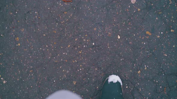 Feet in Boots Walk Fast Along Dark Asphalt Road with Sleek