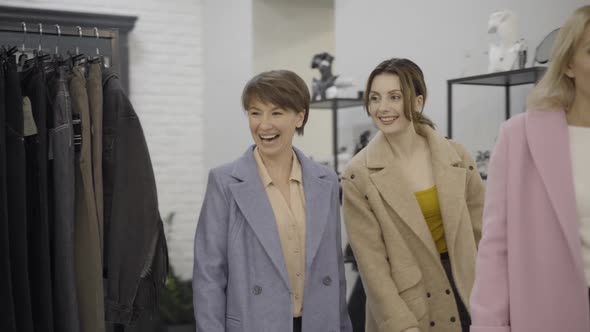 Three Confident Beautiful Women Entering Clothing Store, Talking and Smiling. Portrait of Rich