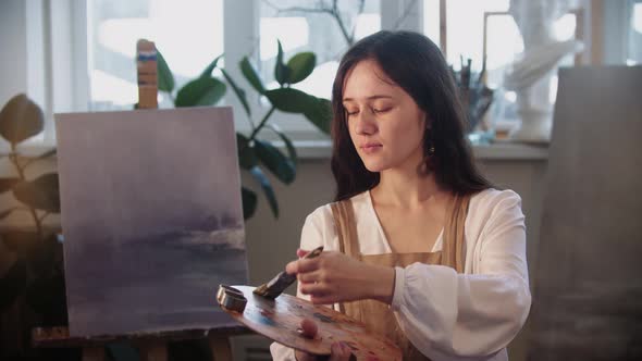 Young Woman Artist Picks the Color on the Brush From the Palette