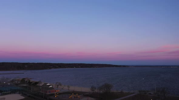 an aerial view over an empty park looking at the bay during a beautiful sunrise. The sky is pink and