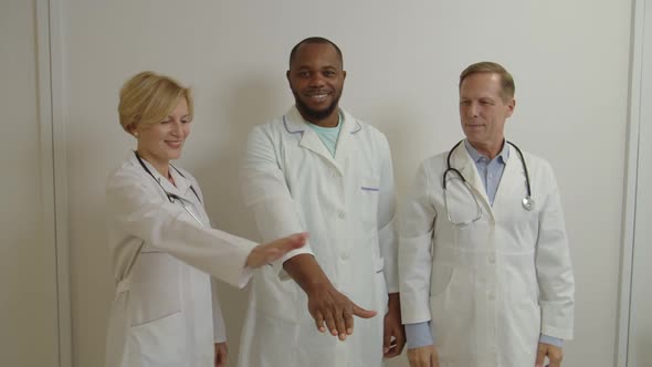 Cheerful Diverse Multiracial Healthcare Workers in Lab Coats Stacking Hands in Medical Clinic