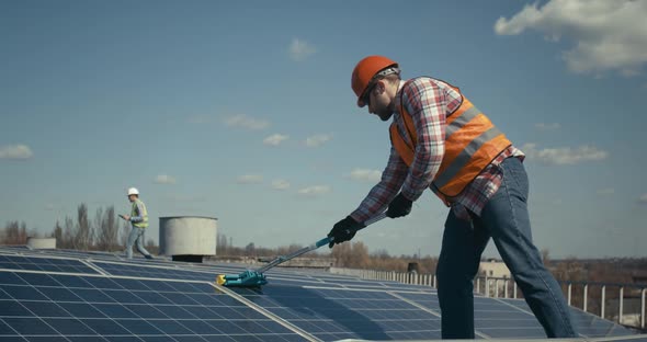 Technician Cleaning Solar Panels on Flat Roof