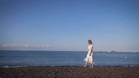 Slender Young Woman Against the Background of the Mediterranean Sea. Walk on a Summer Day Along the