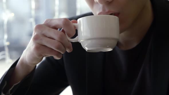 Close-up Portrait of a Serious Good-looking Guy Taking a Sip From a Cup of Tea in a Cafe