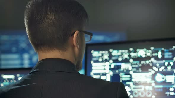 Back View of Programmer Working on Computer in Dark Digital Office