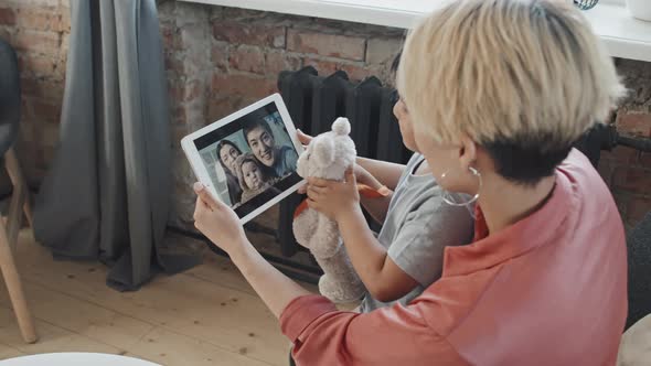 Mother and Little Son Video Chatting with Asian Family of Three