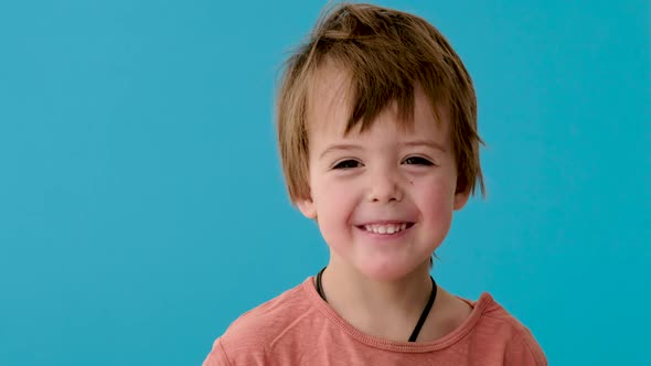 Little Boy in Orange T-shirt Smiles on Turquoise Background