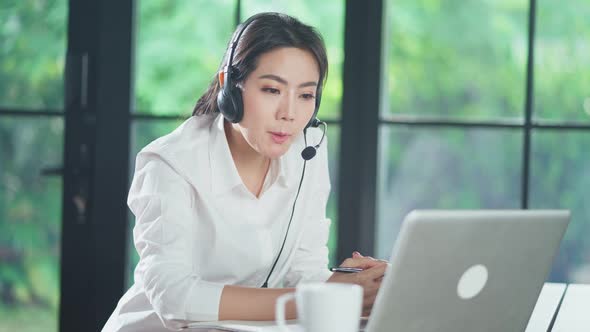 Asian business woman using computer talking to colleague team about plan in video conference at home