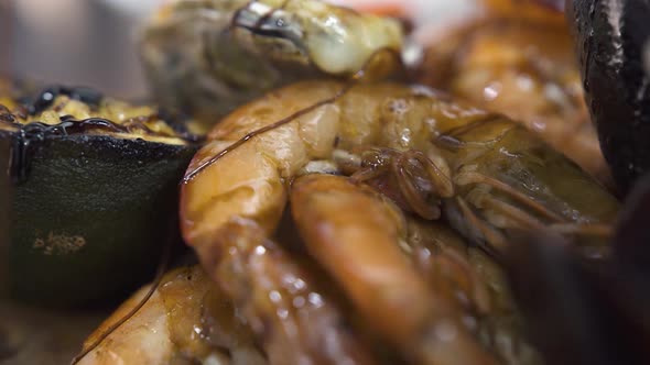 Pouring Sauce on Pile of Grilled Royal Prawns and Mussels