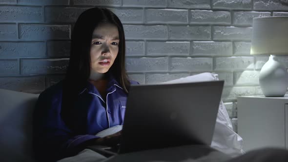 Woman Lying in Bed Working Hastily on Laptop, Trying to Meet Deadline, Overhours