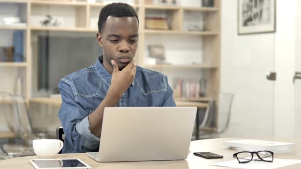 Pensive AfroAmerican Man Thinking and Working on Laptop