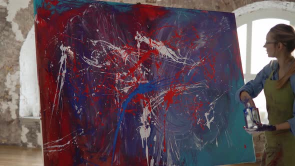 Woman Works on Abstract Painting Sprinkles Paints on Canvas Emotionally