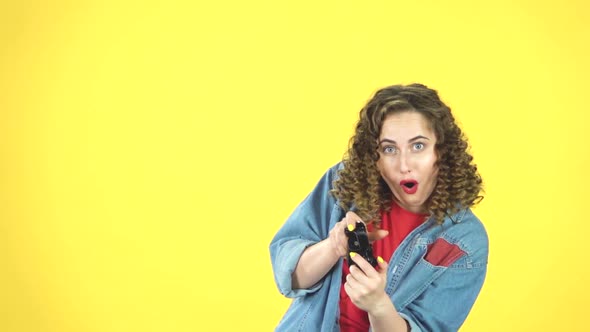 Young Woman Playing a Video Game Using a Wireless Controller on Yellow Background, Slow Motion