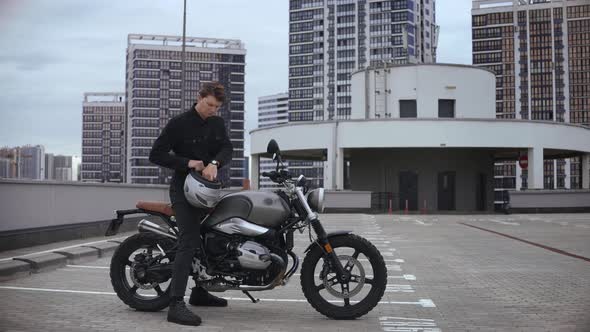 Man Wears Helmet and Starts Motorbike on Top of the Multilevel Parking