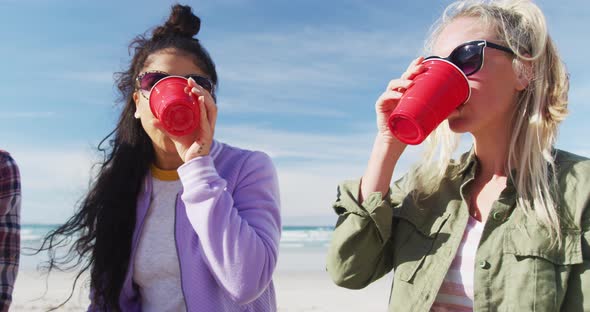 Happy group of diverse female friends having fun, having picnic at the beach