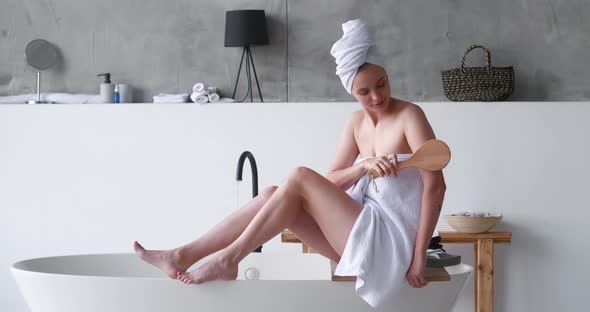 Gorgeous Blonde Woman with Eyes Closed in Pleasure Wrapped in a White Bath Terry Towelmassages Her