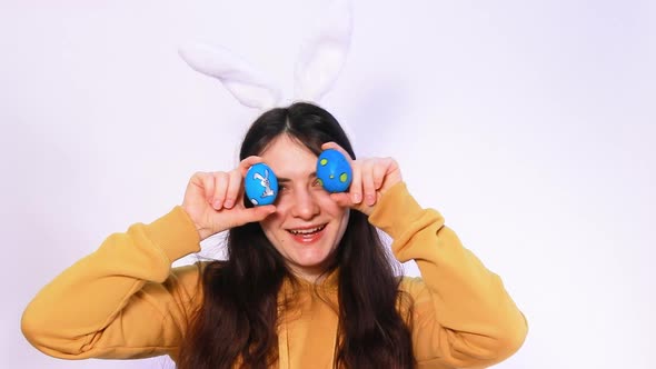 Funny Girl with Rabbit Ears on Her Head Plays with Easter Blue Eggs