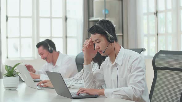 A Man Of Three Asian Call Centre Agents Headache Because His Colleagues Are Talking With Each Other