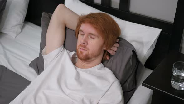 Young Tired Redhead Man Sleeping in Bedroom