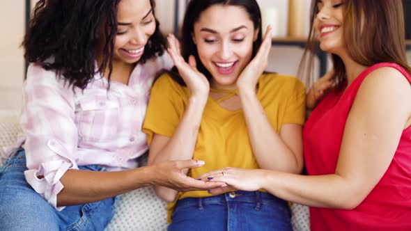 Female hand of happy bride with engagement ring showing it to friends at home