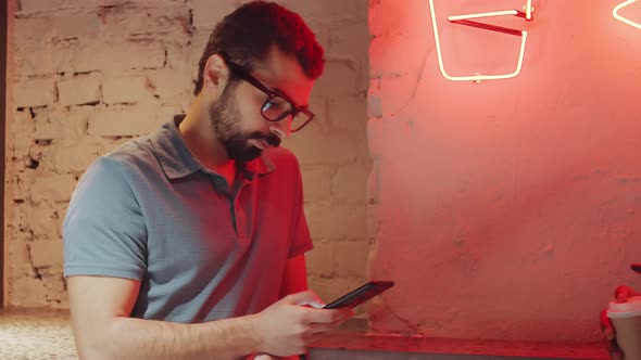 Young Bearded Man Using Smartphone and Posing in Loft Room