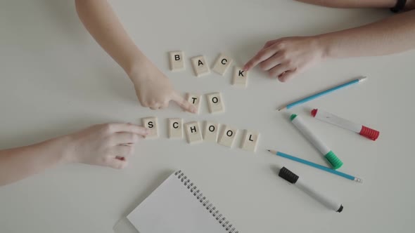 .The Inscription "BACK To SCHOOL" Puzzling with Children's Hands. Close Up of Hands Puzzling Back To