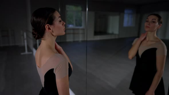 Side View Slim Young Woman Looking at Reflection in Mirror Standing in Dance Studio Smiling