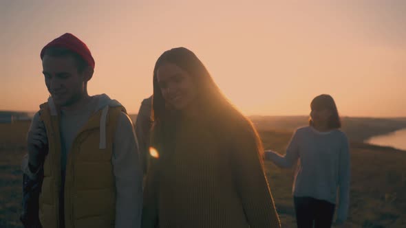 Happy Couples Walk Along Hill To Campsite at Sunset