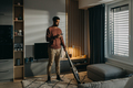 Young man hoovering carpet with vacuum cleaner in living room - PhotoDune Item for Sale