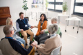 Group of senior people sitting in circle during therapy session, holding hands and praying together - PhotoDune Item for Sale