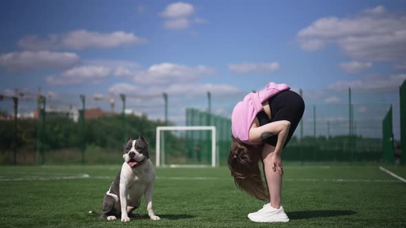 Wide Shot Young Woman Bending in Slow Motion Exercising Outdoors As Dog Distracting Owner