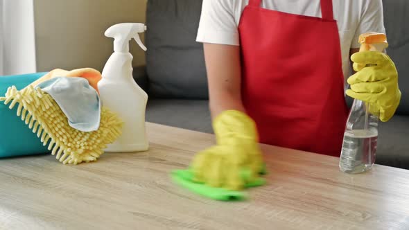 Woman in an Apron and Protective Gloves Washes and Polishes the Countertop Thoroughly