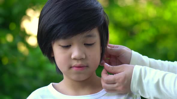 Mother Inserting Hearing Aid In The Ear Of Her Son