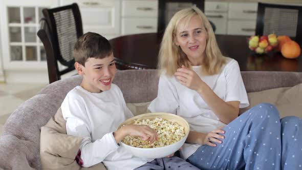 Mother and Son Are Sitting on the Couch Watching Television With Popcorn