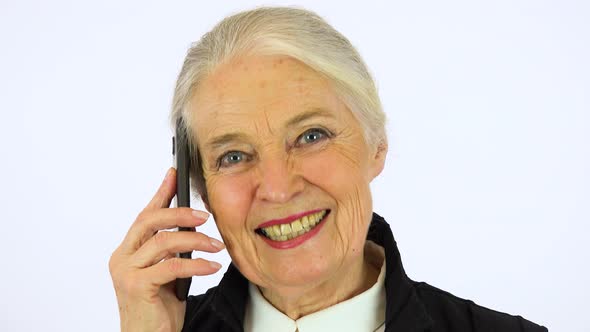 An Elderly Woman Talks on A Smartphone and Looks at The Camera