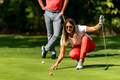 Couple playing golf, young woman reading green, getting ready to putt - PhotoDune Item for Sale
