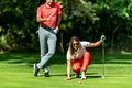 Couple playing golf, young woman reading green, getting ready to putt - PhotoDune Item for Sale