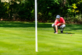 Young golfer playing golf on a beautiful sunny day, reading green - PhotoDune Item for Sale