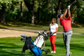 Golfing couple at a tee box, enjoying a game of golf on a beautiful sunny day, man hitting a ball - PhotoDune Item for Sale